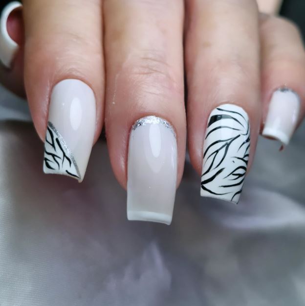 Unhas brancas decoradas com desenhos florais.