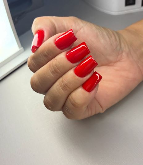 Unhas vermelhas com pedrarias delicadas.