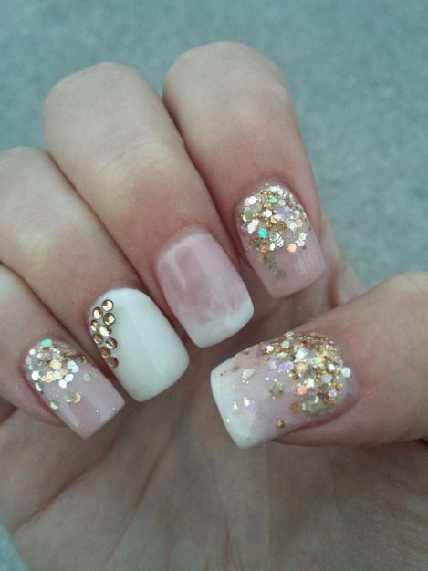 Unhas brancas decoradas com detalhes dourados.