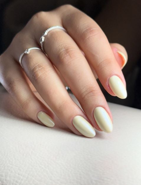 Unhas amarelas pastel com acabamento delicado.
