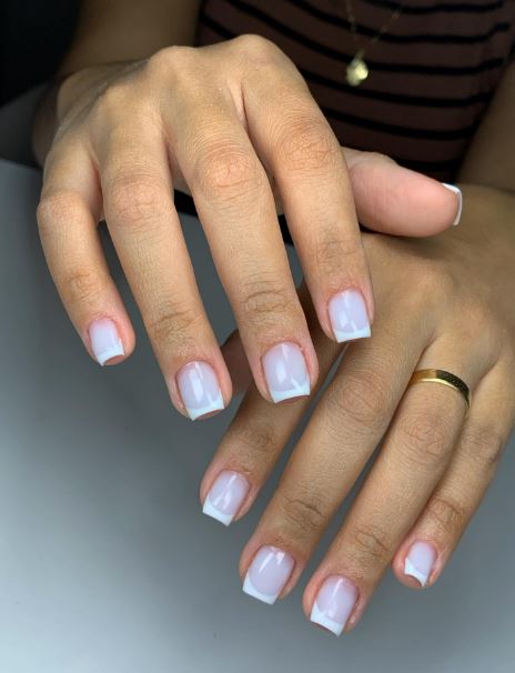 Unhas brancas decoradas com pedrarias delicadas.