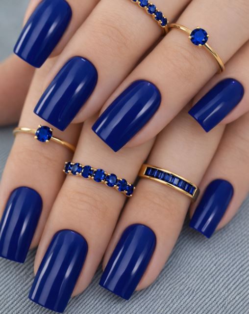 Nail art em unhas azuis com pedrarias delicadas.